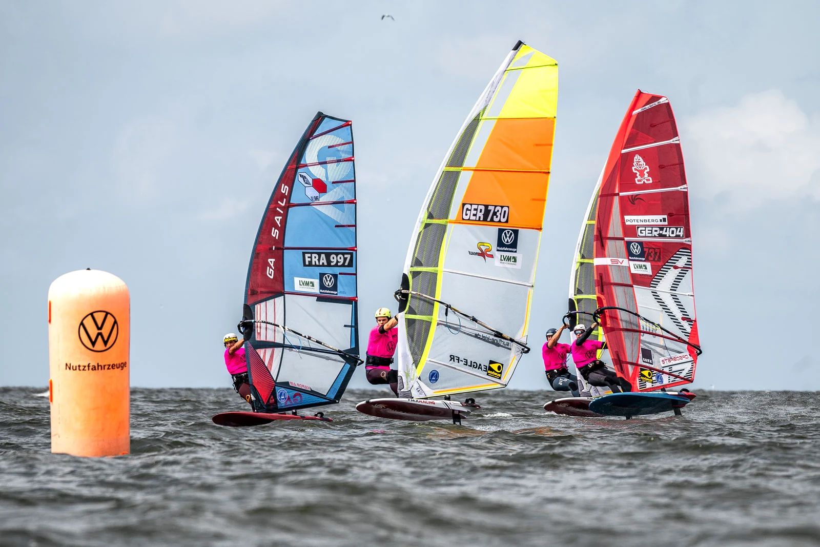 Quatre planchistes en windfoil, portant des dossards, contournent une bouée de virage pendant une course longue distance à la California Windsurf Cup