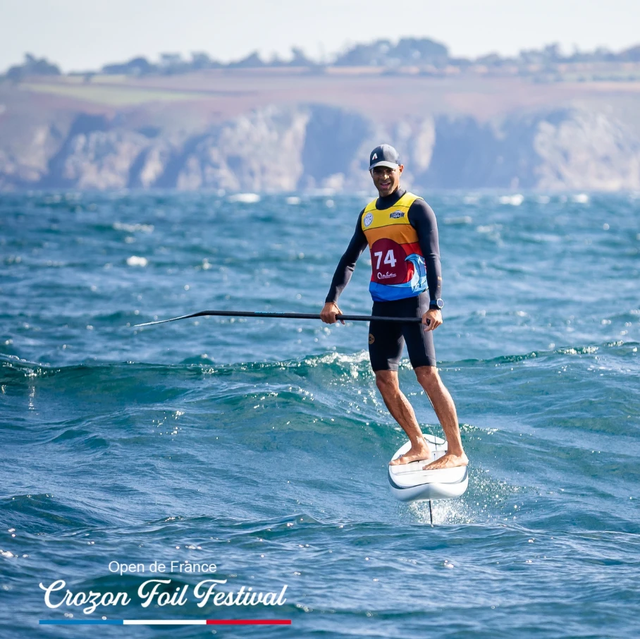 Romuald Mamadou en SUP-foil, en train de prendre une vague pendant un parcours downwind du Crozon Festival