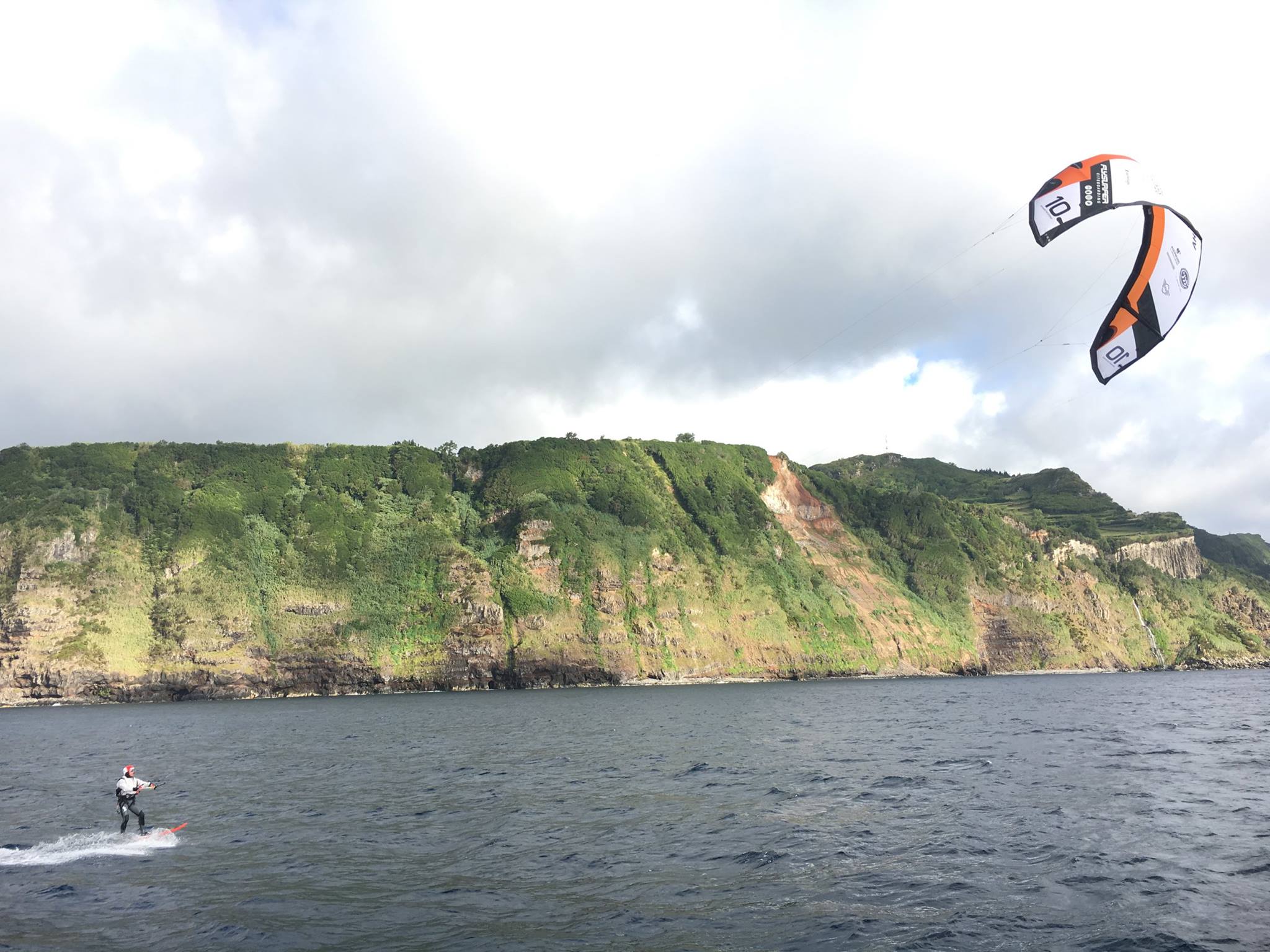 Francisco Lufinha en kitesurf foil longeant une haute falaise verdoyante lors de sa traversée vers les Açores
