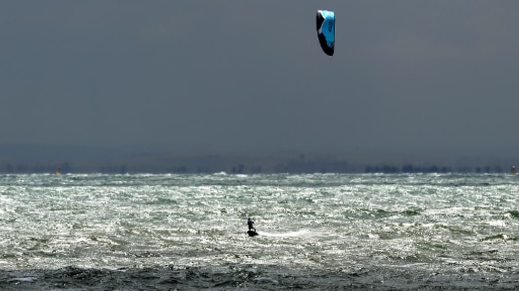 Kitesurfeur seul sur l'eau en petit de loin qui navigue au large
